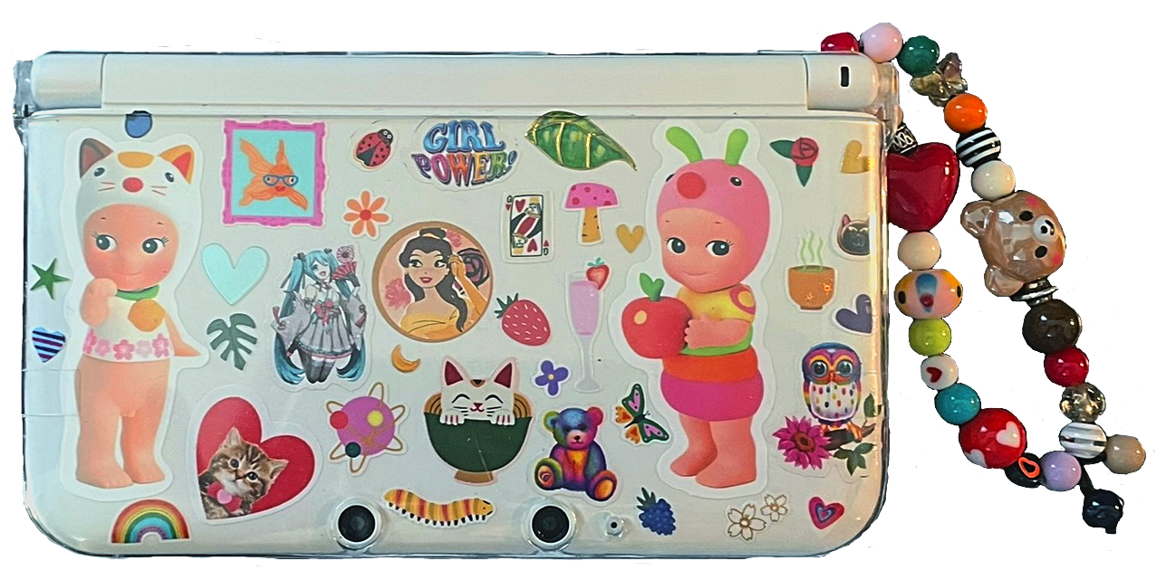 A white Nintendo DS XL adorned in stickers, with a beaded strap